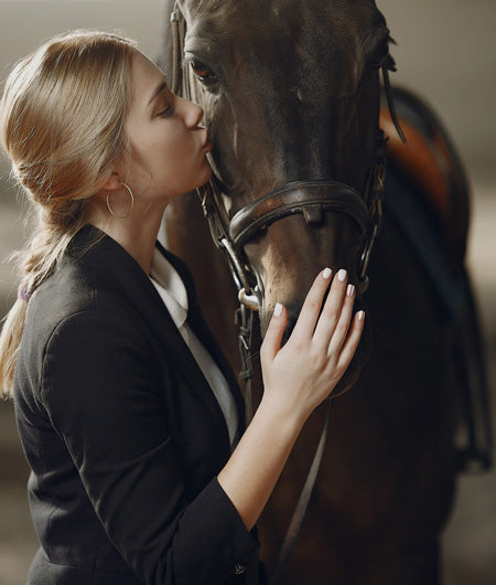 Image of a trainer kissing her horse